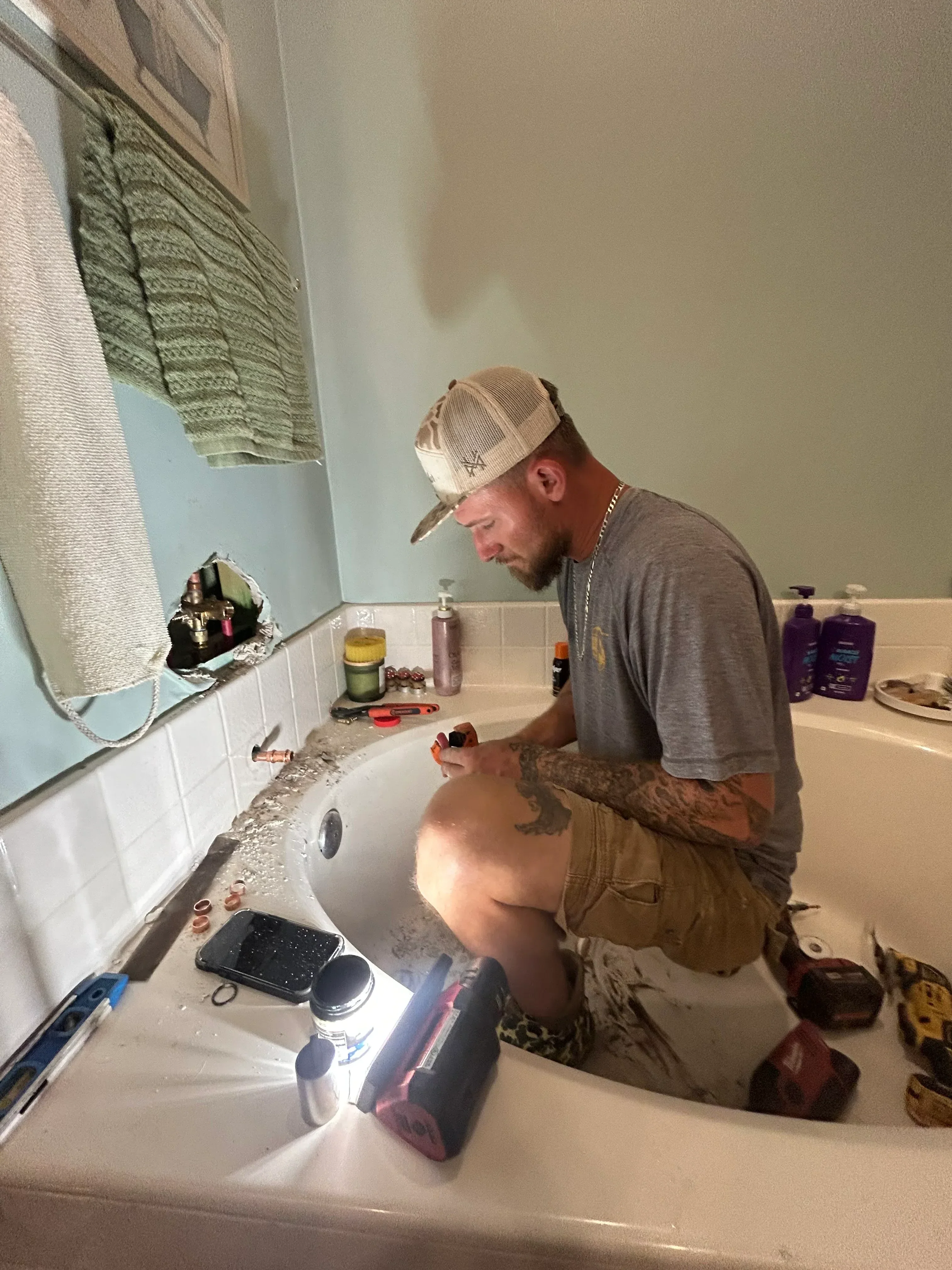 Plumber working on under-sink plumbing connections and supply lines in bathroom vanity