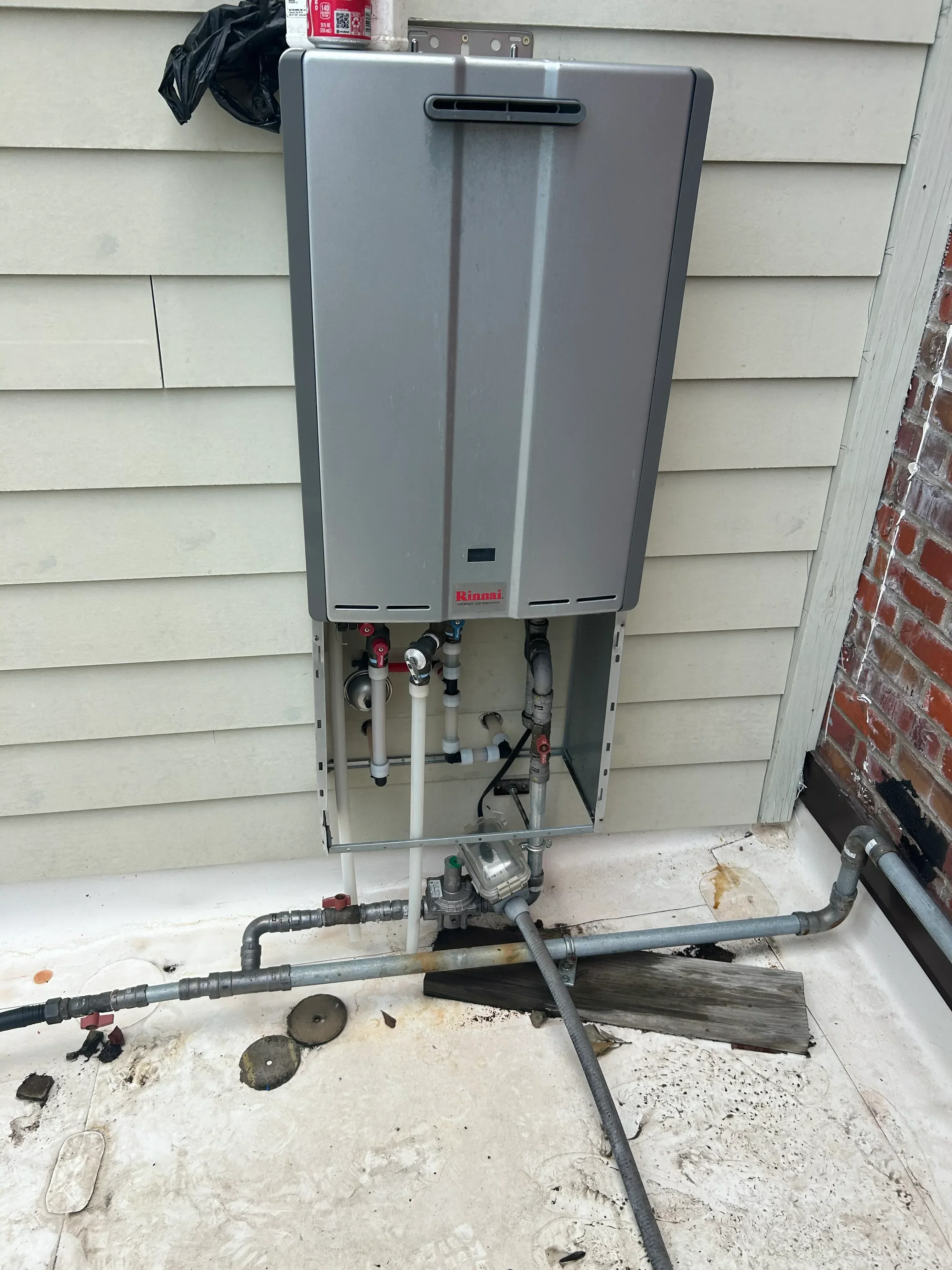 Rinnai tankless water heater with copper piping, mixing valves, and PVC connections installed on wall