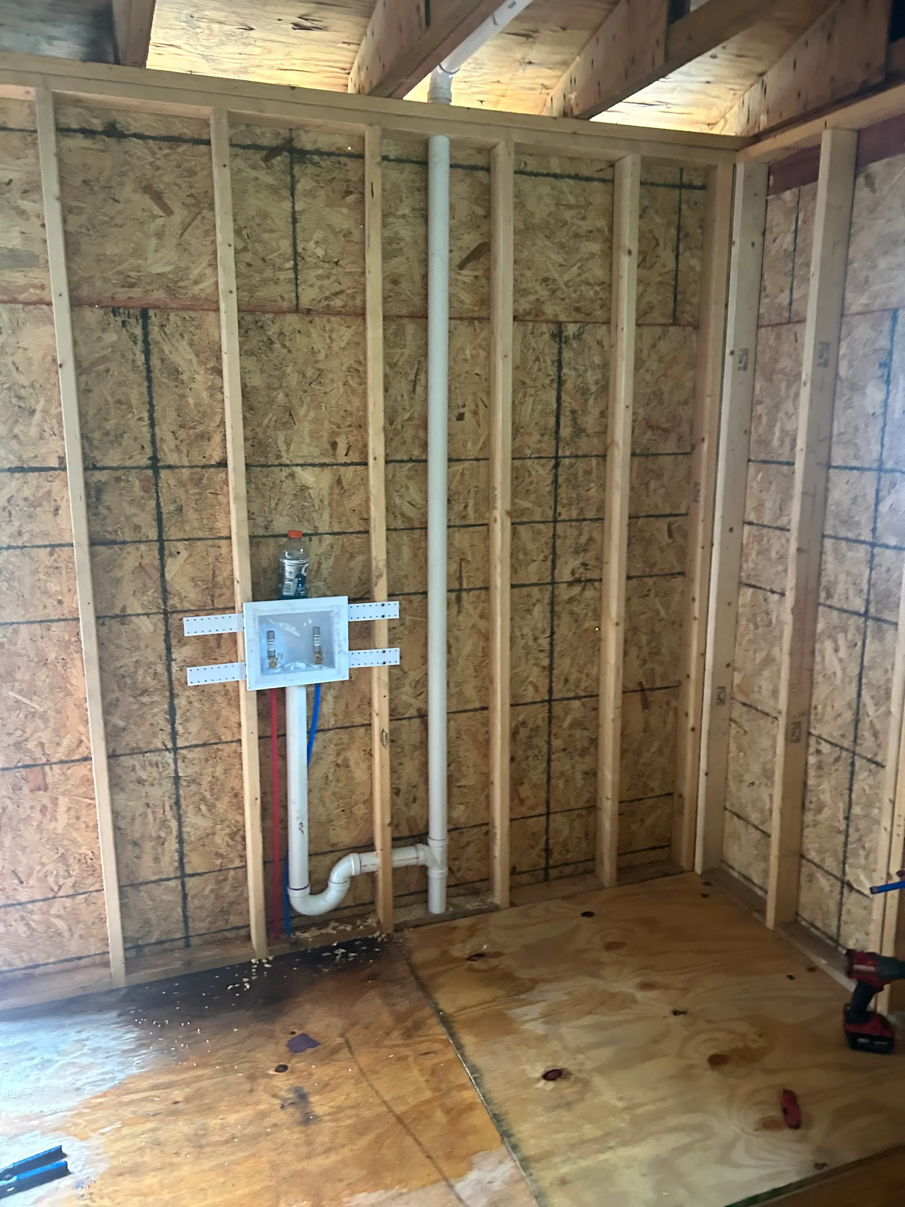 PEX supply lines and PVC drain lines installed through floor joists with proper spacing and support brackets