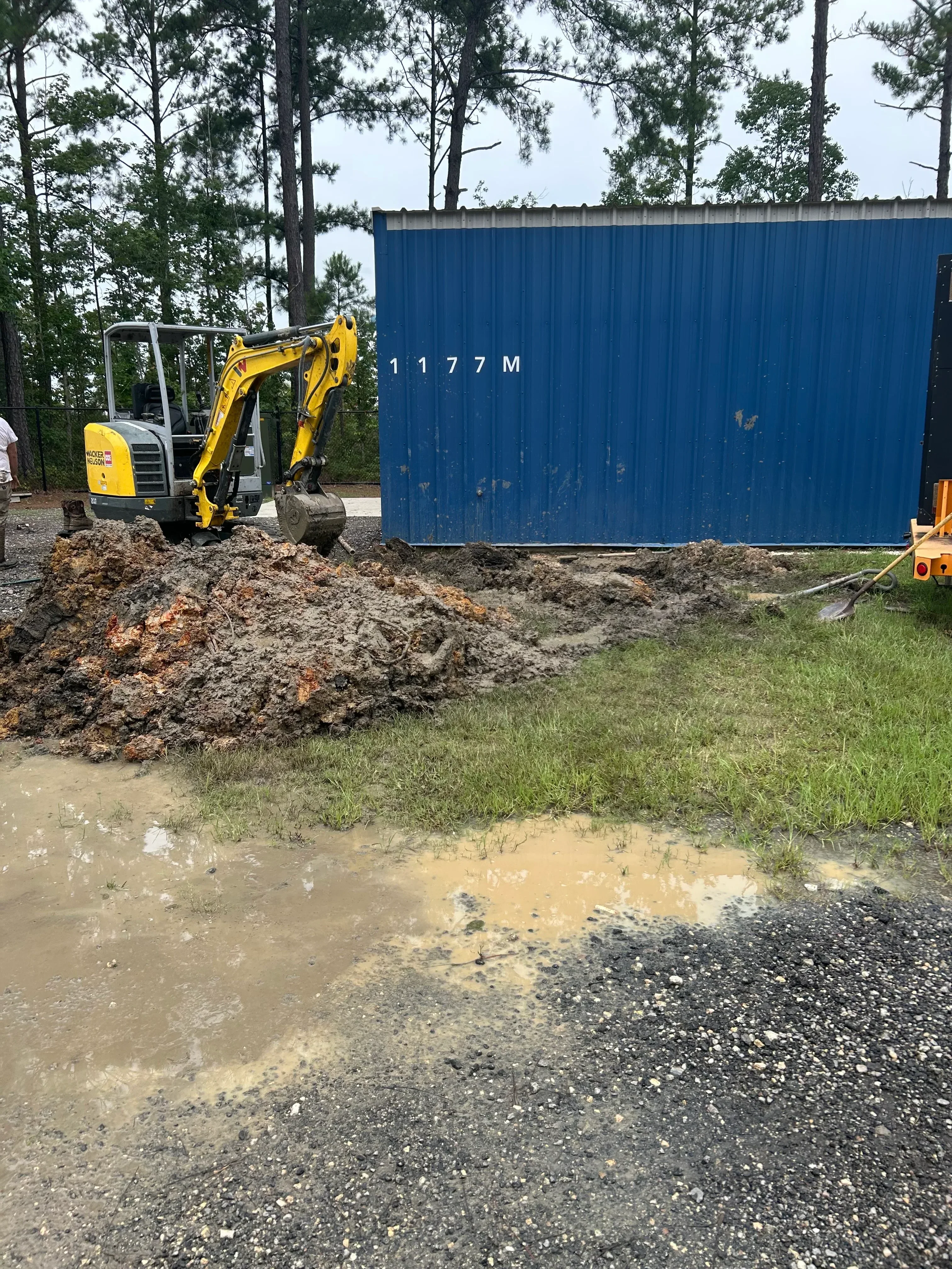 Blue septic tank installation with excavation equipment on residential property