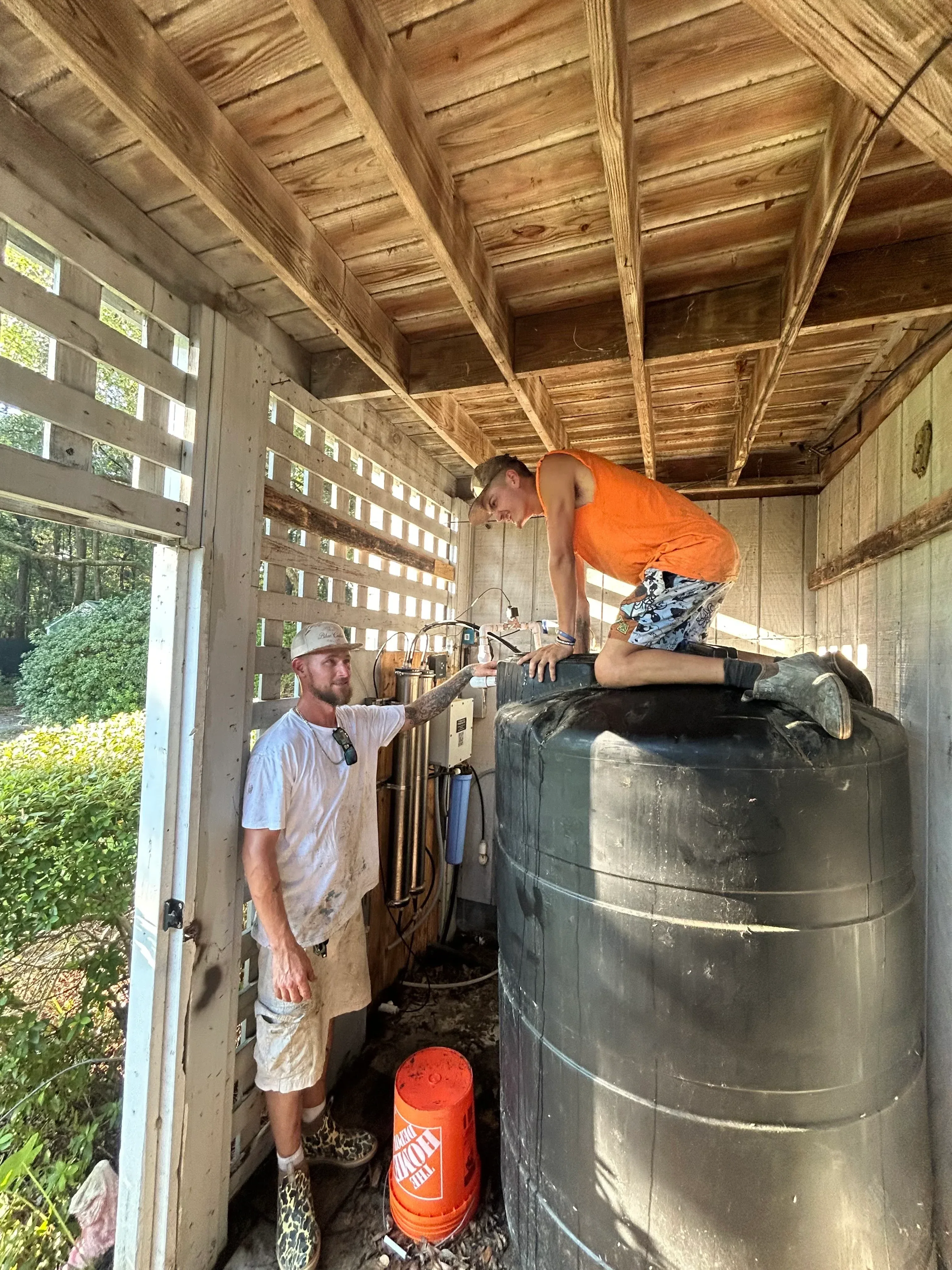 Water heater tank installation with plumbing connections and mounting hardware setup