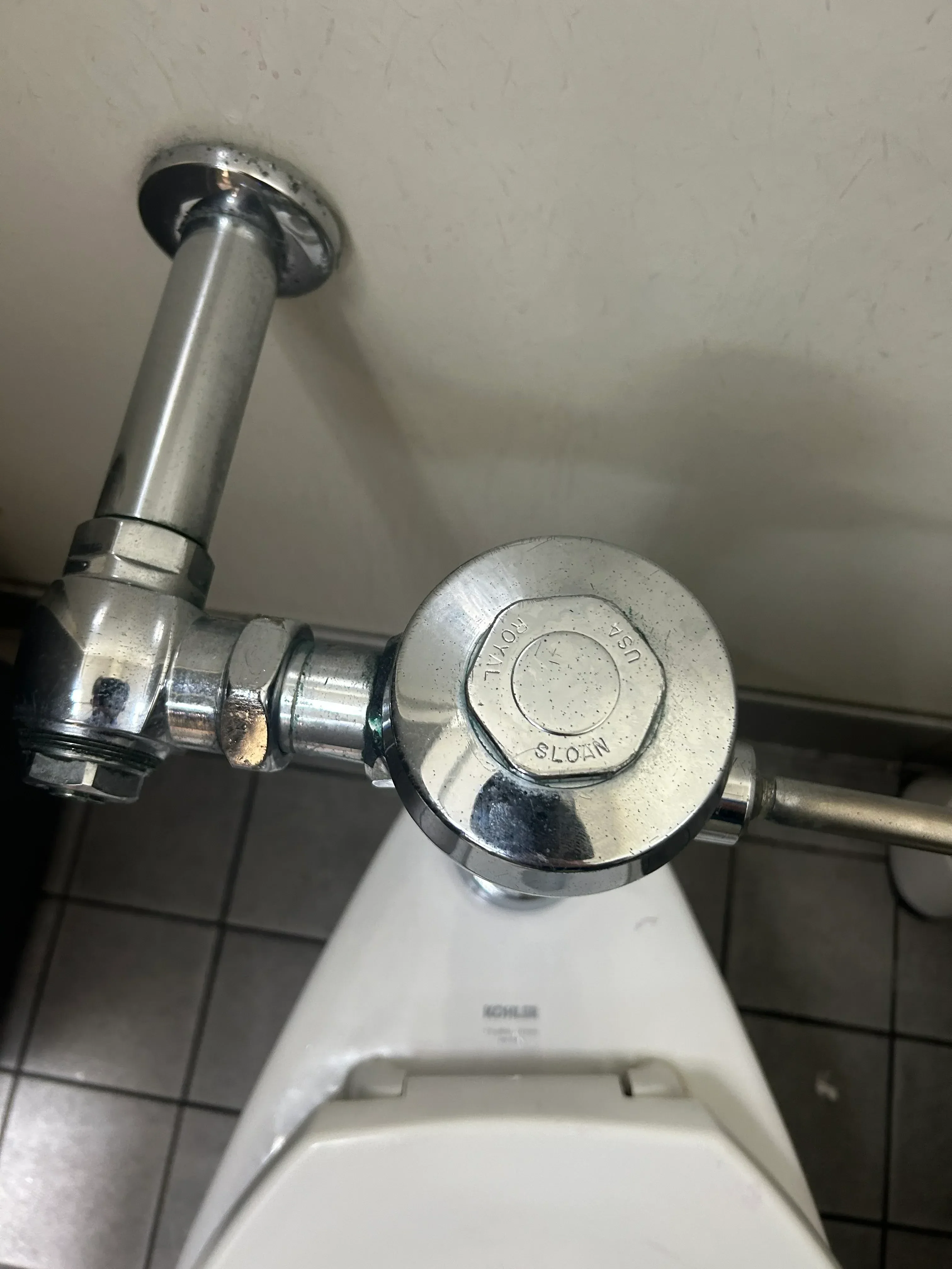 Chrome shower valve with pressure-balancing cartridge and round trim ring mounted on tile wall