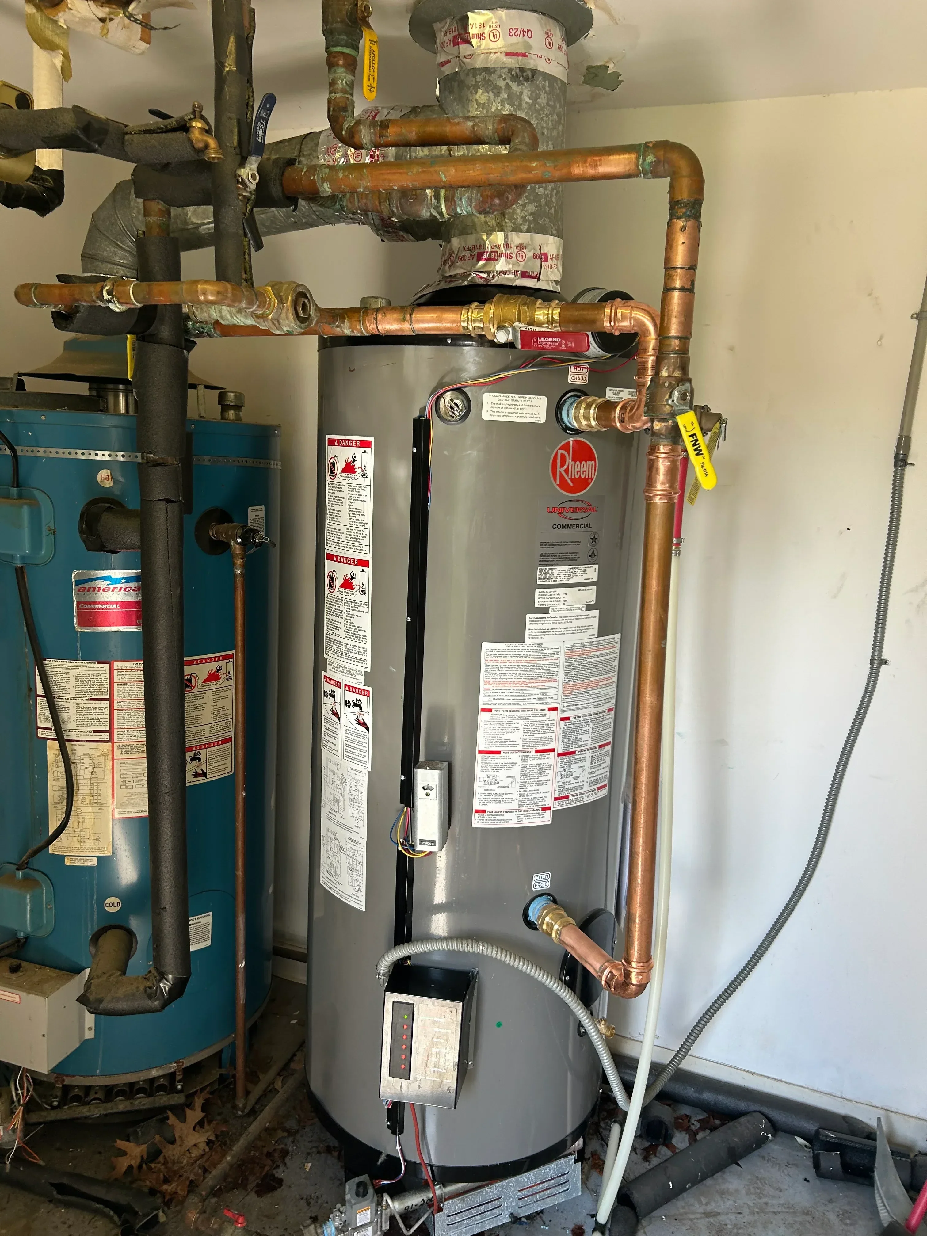 Installed water heater with copper piping, pressure relief valve, and electrical connections