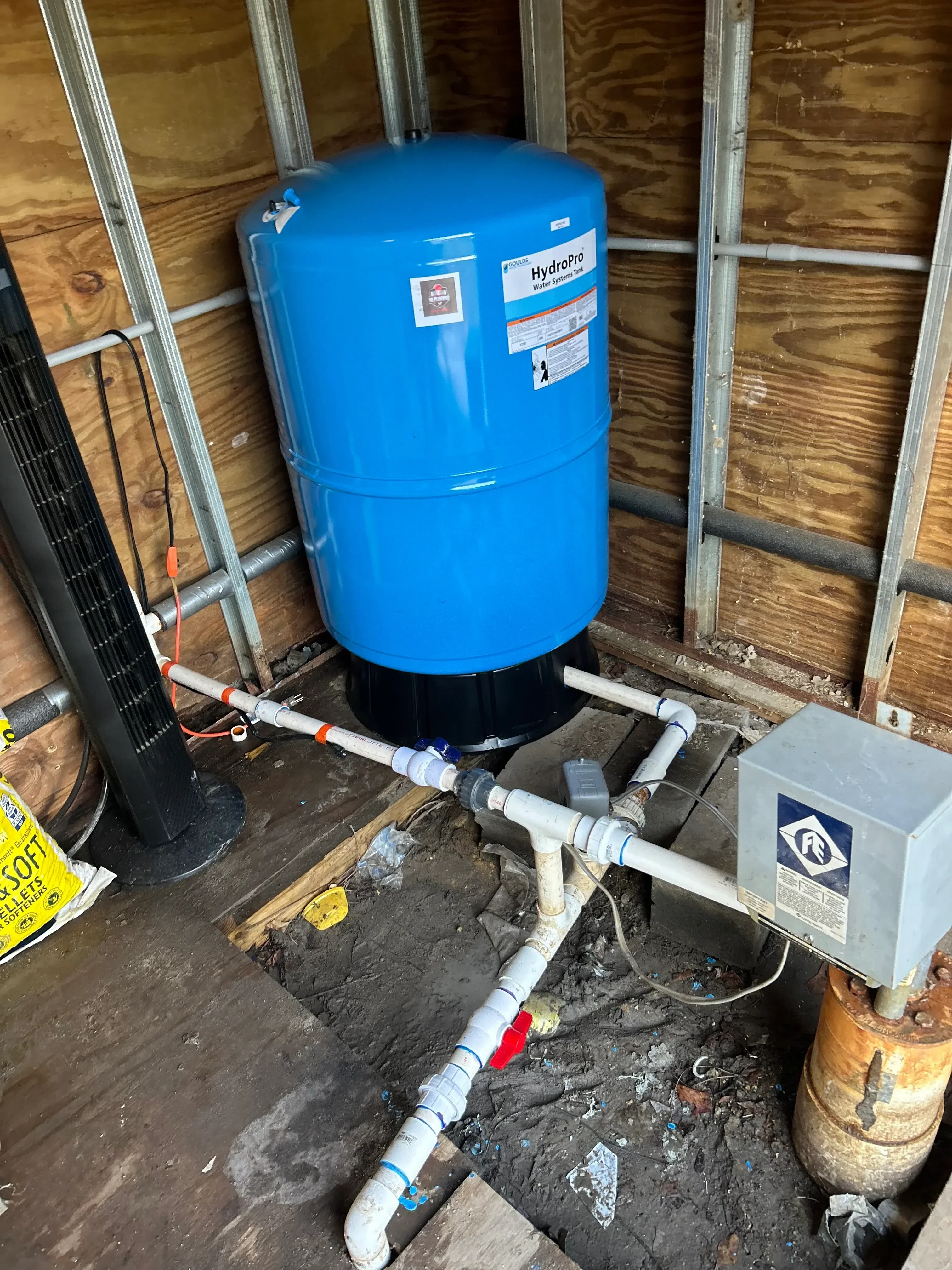 Blue pressure tank with pump system, PVC piping, check valves, and pressure switch control box installation