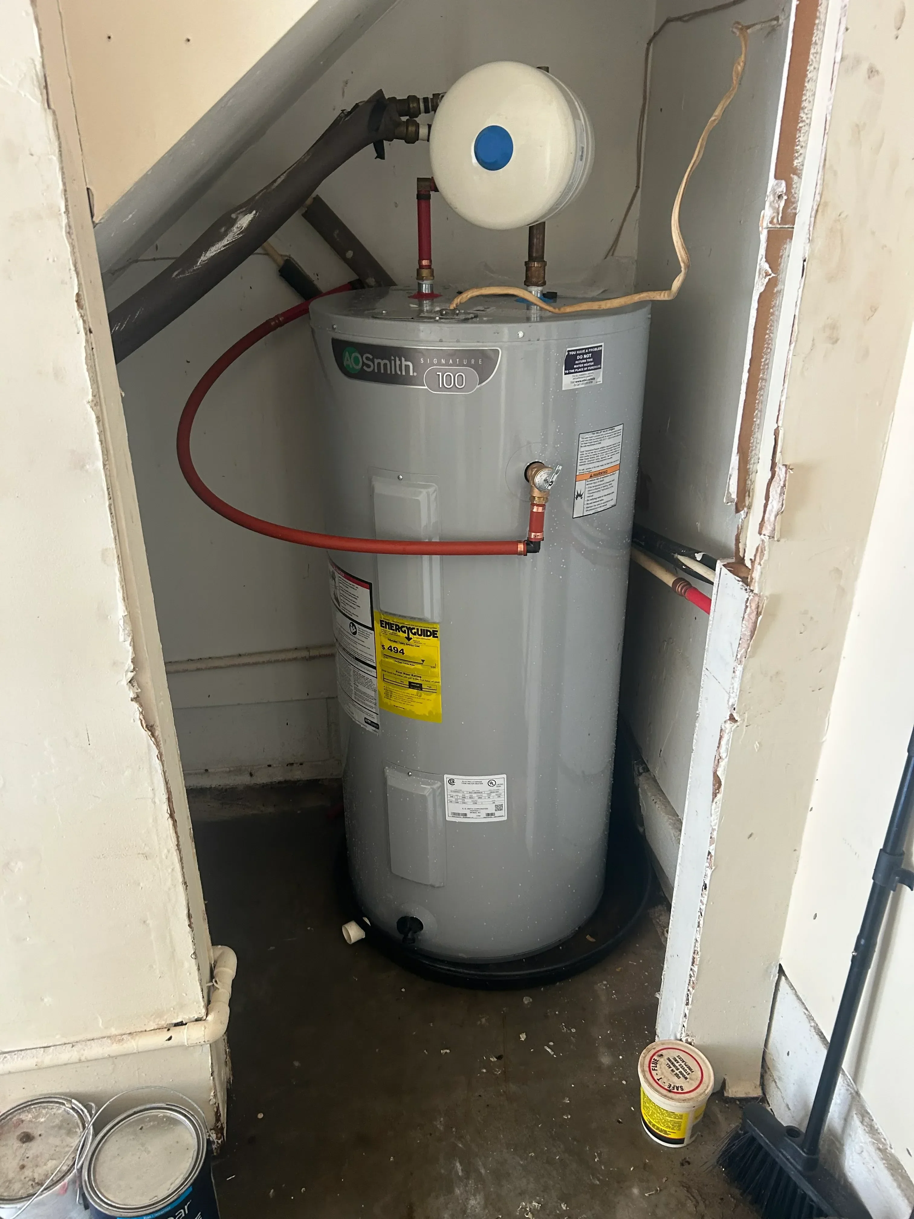 Smith electric water heater with red isolation valves, expansion tank, and pressure relief valve installed in basement