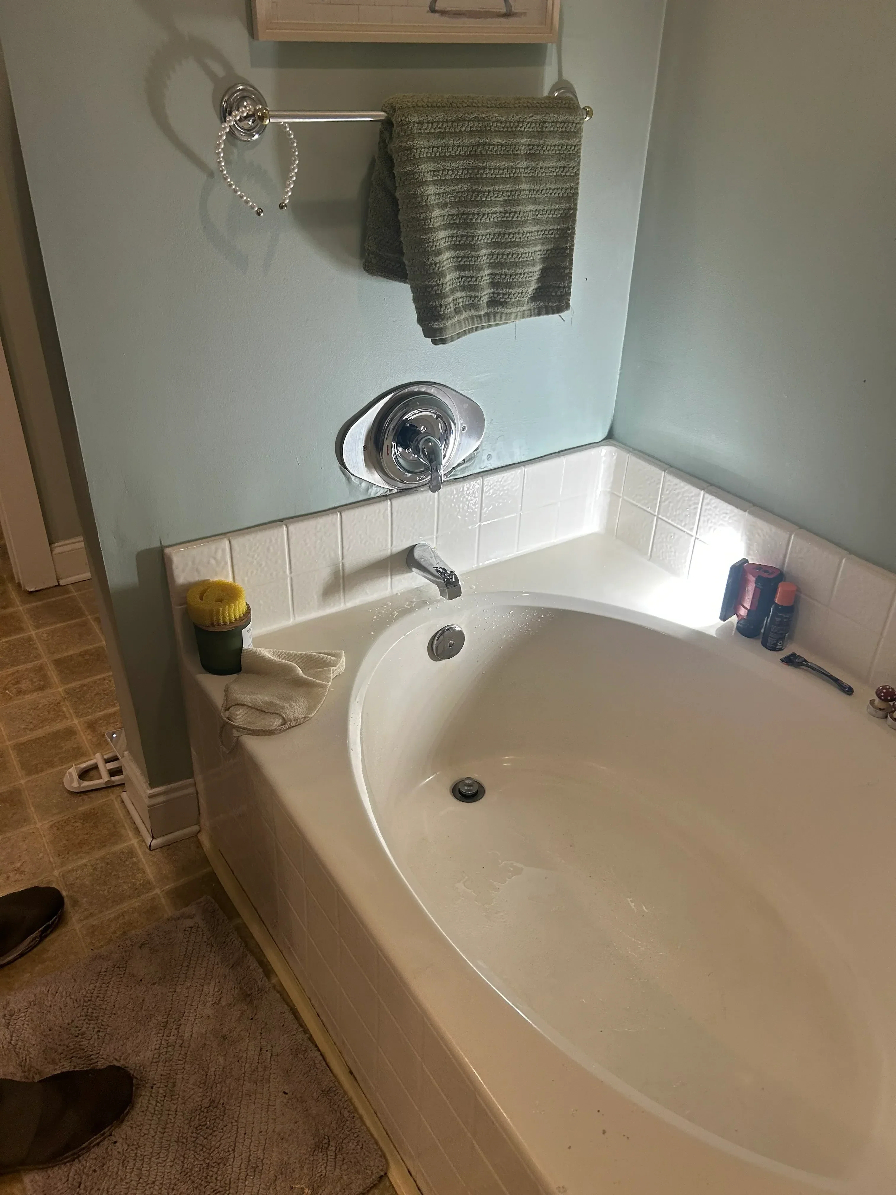Installed acrylic soaking tub with chrome fixtures, white subway tile surround, and plumbing connections