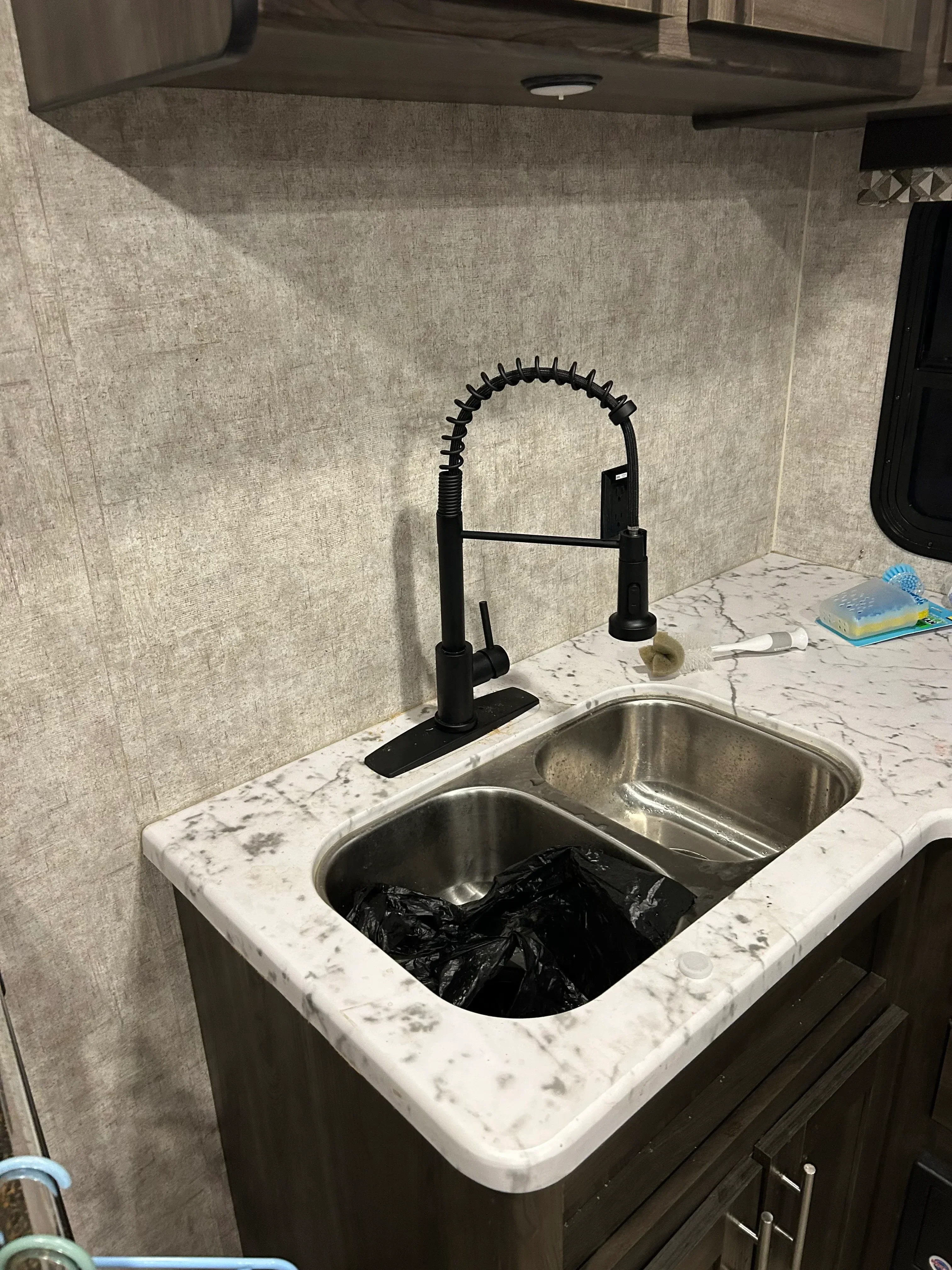 Stainless steel double-basin kitchen sink with spray faucet installed in white speckled quartz countertop